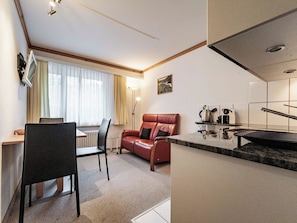 A compact living space with a kitchenette, a dining area with a table and chairs, and a seating area with a sofa. - Paradies 012 Appartement/Fewo,  , 3-Bettwohnung 3-Bettwohnung by Interhome (Arosa)