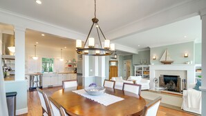 A spacious dining area with a wooden table, white upholstered chairs, and a central chandelier. - 4br/4ba Beachfront Retreat With Hot Tub and Sauna (Moclips)