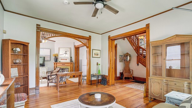 A spacious living room with hardwood floors, a round coffee table, and a staircase leading to an upper level. - Historic Queen Anne Omaha Home in Field Club (Omaha)