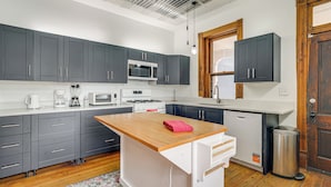 A modern kitchen with grey cabinets, a wooden island, and a stainless steel trash can. - Historic Queen Anne Omaha Home in Field Club (Omaha)