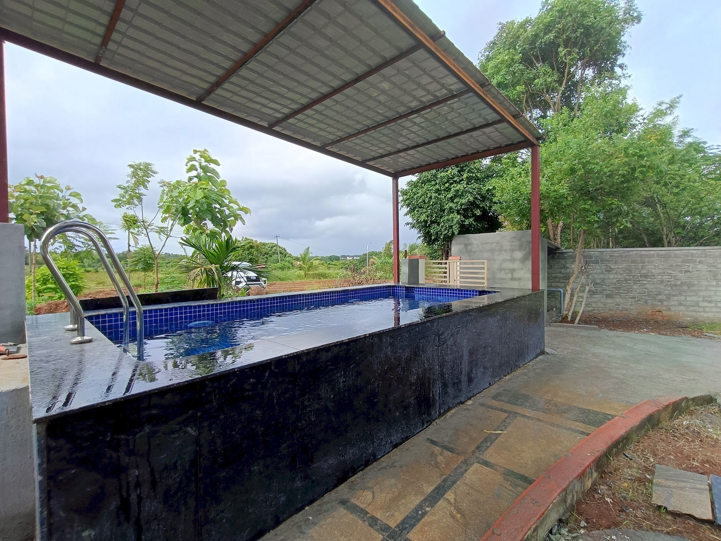 En swimmingpool med et metal tag og en fliseterrasse.