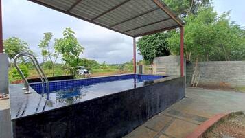 En swimmingpool med et metal tag og en fliseterrasse.
