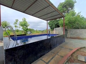 A swimming pool with a metal roof and a tiled deck area.