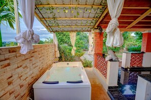 Zona de spa con hidromasaje, pared de ladrillo y vistas a la vegetación.