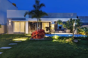 Una casa moderna con piscina, césped cuidado y zona de patio.
