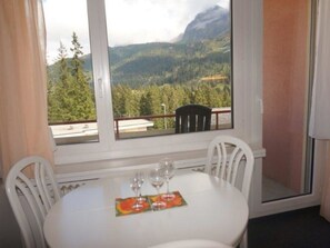 A room with a table set for two, two chairs, and a window with a mountain view. - Paradies 505 Appartement/Fewo, Bad, WC, 2-Bettwohnung 2-Bettwohnung by Interhome (Arosa)