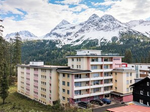 Ein mehrstöckiges Hotel mit einem zentralen Atrium, einem Parkplatz und einem Berg im Hintergrund.