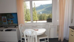 A room with a dining table and chairs, a television, and a window with a view of mountains. - Paradies 505 Appartement/Fewo,  , 2-Bettwohnung 2-Bettwohnung by Interhome (Arosa)
