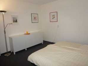 A bedroom with a bed, a white dresser, a floor lamp, and two framed pictures on the wall. - Paradies 505 Appartement/Fewo, Bad, WC, 2-Bettwohnung 2-Bettwohnung by Interhome (Arosa)