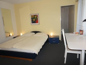 Ein Hotelzimmer mit Bett, Nachttischen, Schreibtisch und Stuhl.