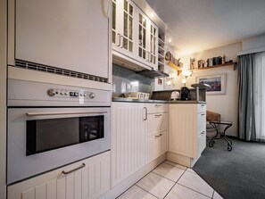 Eine kompakte Küche mit Einbauofen, Mikrowelle und Kaffeemaschine.