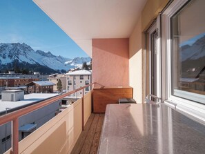 A balcony with a view of snow-capped mountains, a wooden bench, and a metal railing. - Paradies 607 Appartement/Fewo,  , 2-Bettwohnung 2-Bettwohnung by Interhome (Arosa)