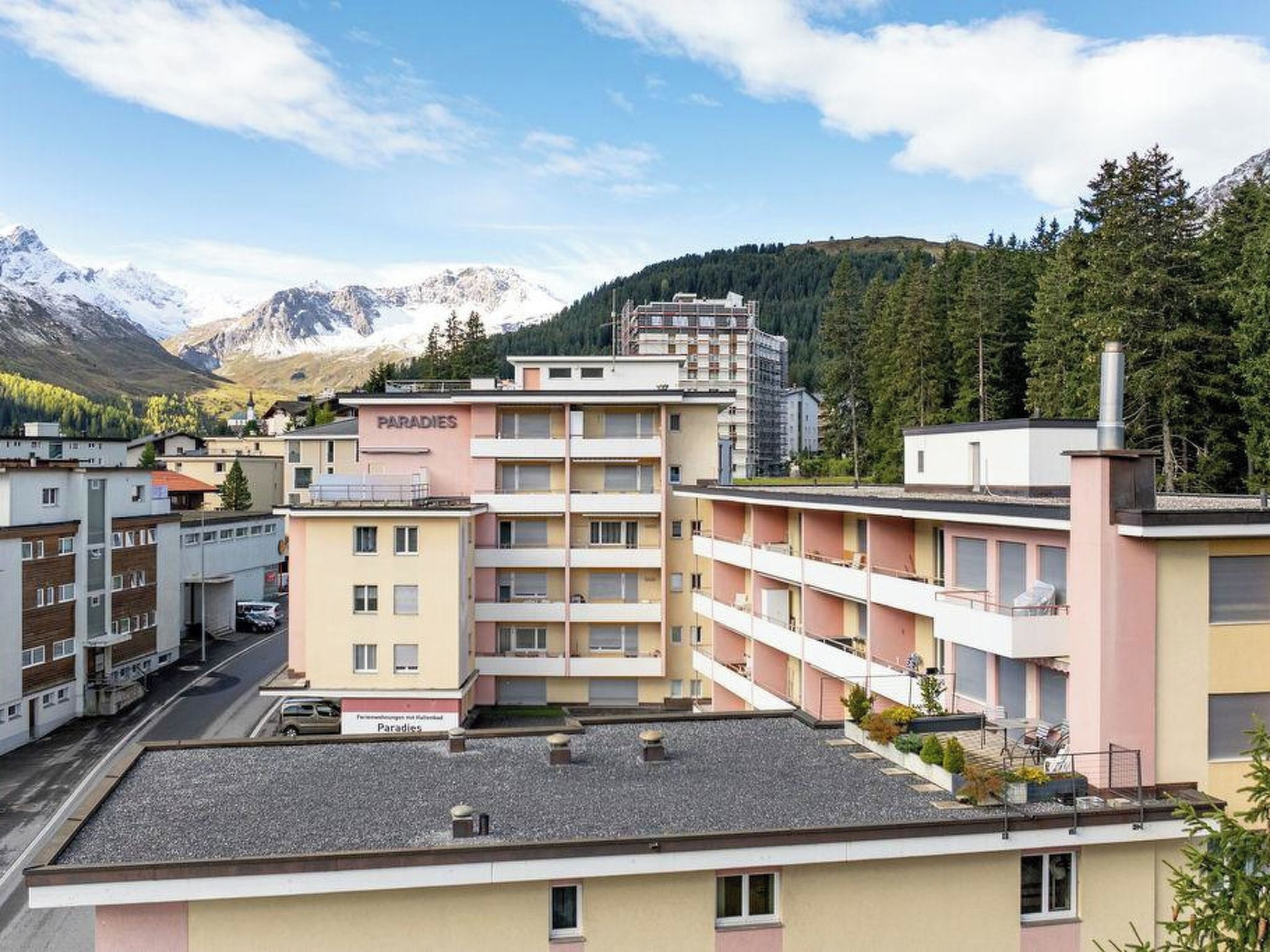 A multi-story hotel with balconies and a view of mountains.