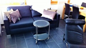 Ein modernes Wohnzimmer mit einer Couch, einem kleinen runden Tisch und einem Sessel.