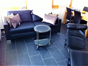 Ein modernes Wohnzimmer mit einer Couch, einem kleinen runden Tisch und einem Sessel.
