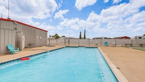 A rectangular swimming pool with a tiled edge, surrounded by a concrete deck. There are two blue chairs and a red floating ring near the pool. - Peaceful, Private Slice of Deep South Texas (San Benito)
