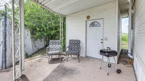 A covered porch with two patterned chairs, a grill, and a white door. - Peaceful, Private Slice of Deep South Texas (San Benito)