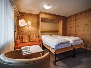 A hotel room with a bed, a sofa, a table, and a lamp. - Paradies 023 Appartement/Fewo,  , 2-Bettwohnung 2-Bettwohnung by Interhome (Arosa)