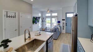 A modern kitchen with a built-in dishwasher, a large island with a sink, and a ceiling fan. - Walk to Beach! North Padre Home w/ Pool Access (Corpus Christi)