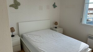 Una camera da letto con un letto, due comodini, una finestra e una lampada a parete.