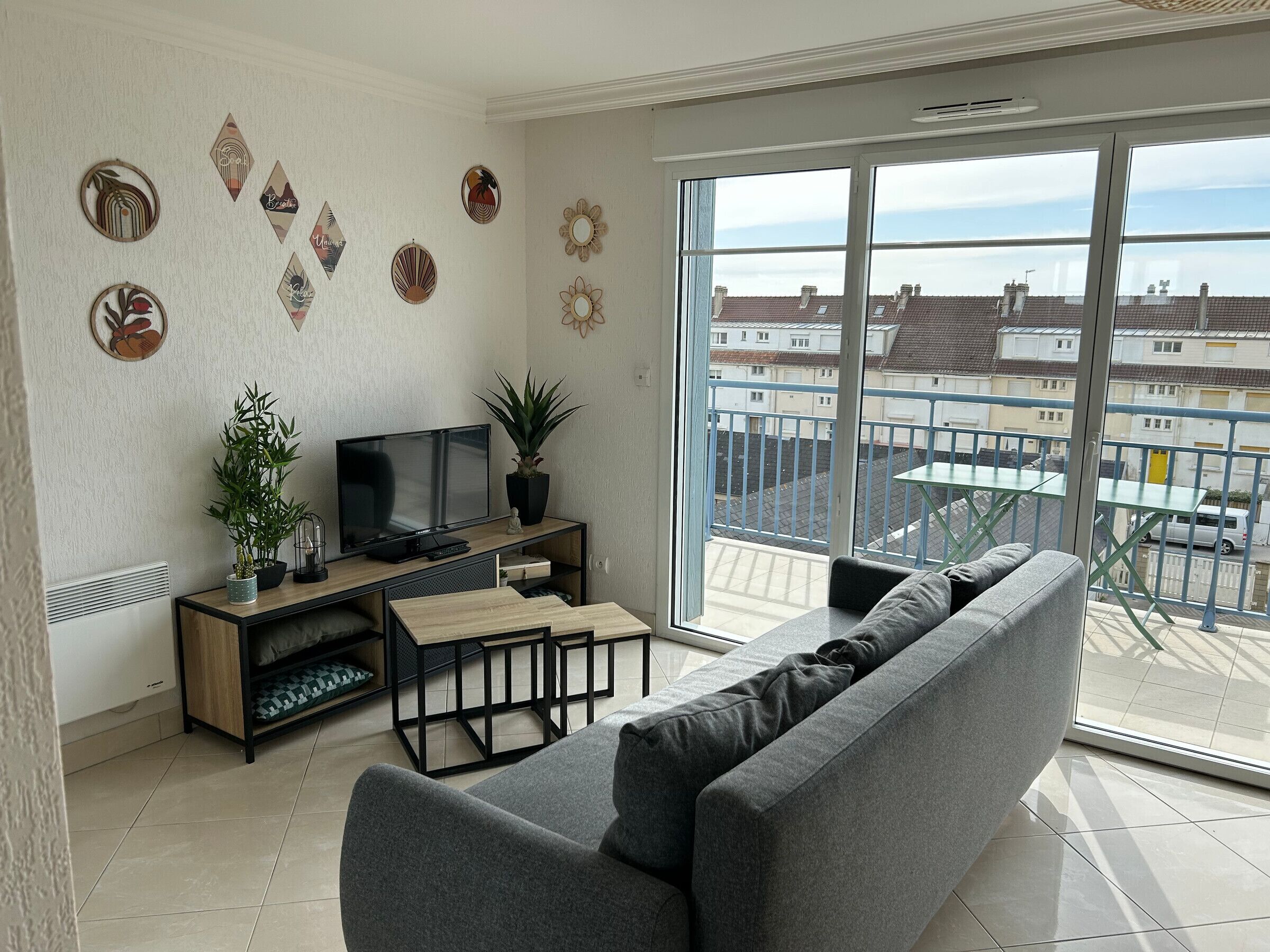 A modern living room with a grey sofa, a flat-screen TV, a wooden coffee table, and decorative wall art.