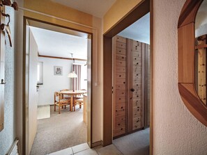 A hallway with a wooden door, a dining area with a table and chairs, and a view into another room. - Paradies 203 Appartement/Fewo,  , 3-Bettwohnung 3-Bettwohnung by Interhome (Arosa)