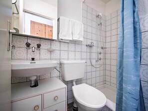 Een badkamer met een wit wastafel, toilet en douche.