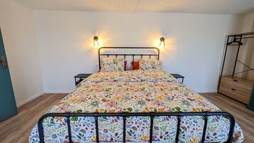A bed with a floral bedspread, two bedside tables, and wall-mounted lights.