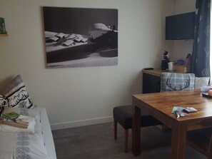 Ein gemütlicher Wohnbereich mit einem Holztisch, einer Couch mit gemusterten Kissen und einem Wandbild.