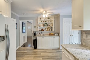 A kitchen with white cabinetry, a granite countertop, and a ceiling fan. - Pinehurst Golf Stay w/ Hot Tub & Game Room (Pinehurst)