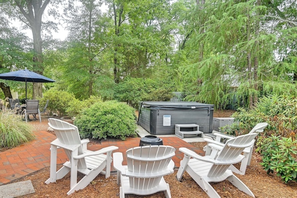 An outdoor patio with Adirondack chairs, a hot tub, and a brick pathway. - Pinehurst Golf Stay w/ Hot Tub & Game Room (Pinehurst)