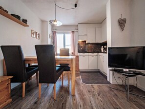 Een compacte woonruimte met een eethoek, een kitchenette en een televisie.