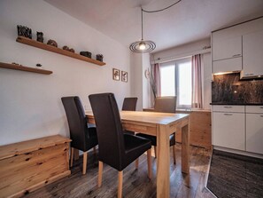 Een moderne keuken met witte kasten, een houten eettafel en zwarte stoelen.