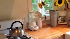 A kitchen with a kettle, a blender, a coffee maker, and a vase with sunflowers. - Steps to Beach & Lake Michigan! Family Retreat (Lakeside)