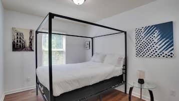 A four-poster bed in a modern room with a glass table and artwork on the walls.