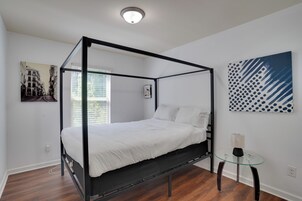 A four-poster bed in a modern room with a glass table and artwork on the walls.