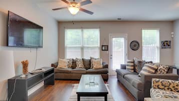 A living room with a ceiling fan, two couches, a coffee table, and a TV.