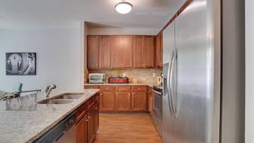 A kitchen with wooden cabinets, a stainless steel refrigerator, a dishwasher, and a microwave.