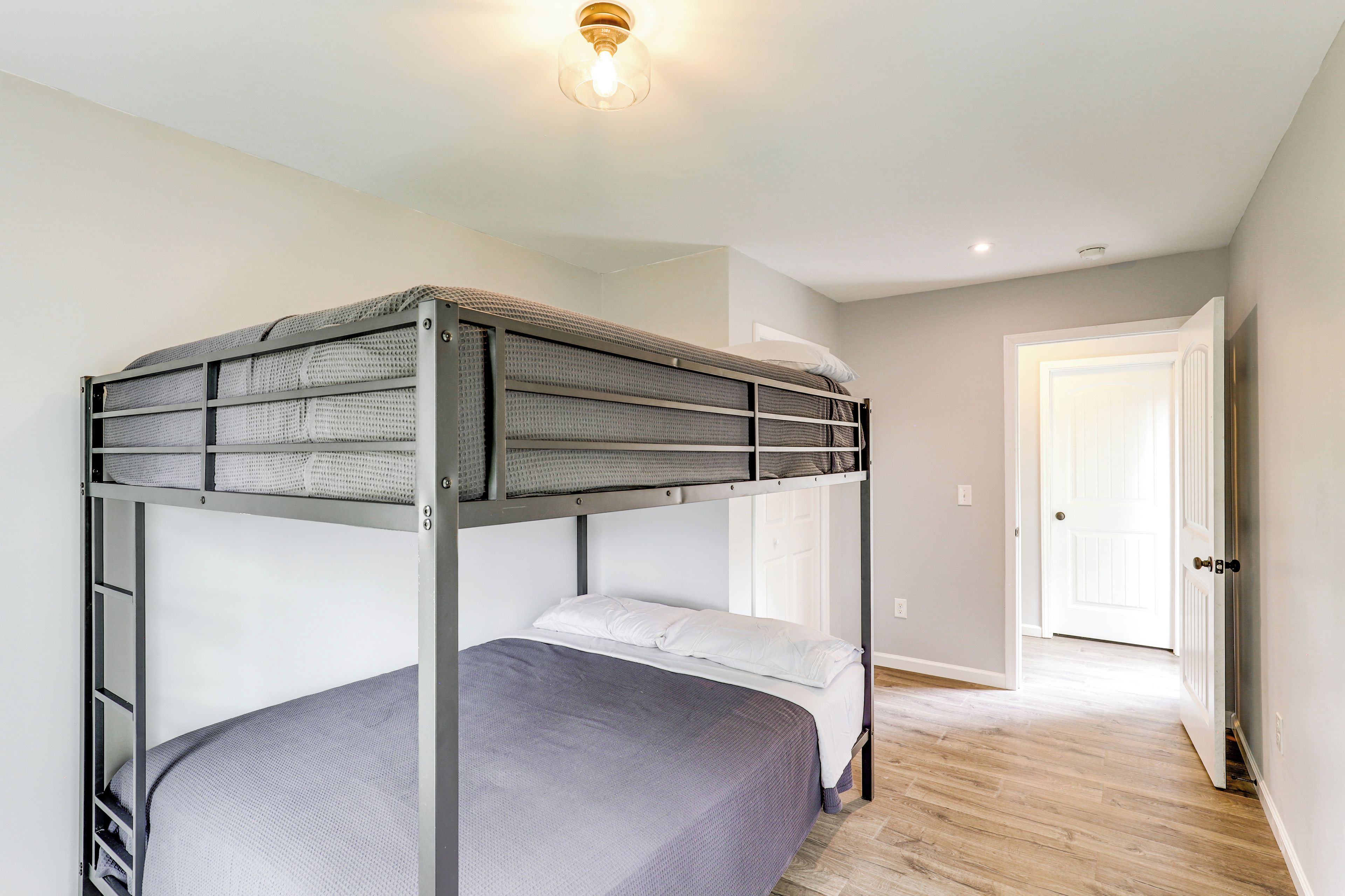 A bunk bed with a headboard, a bedside table, and a door leading to another room.