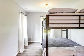 Dormitorio con literas, ventana, cortinas y lámpara.