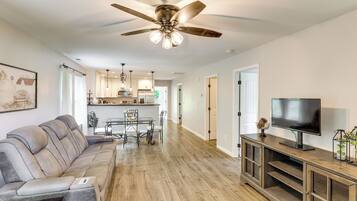 A modern living room with a sofa, TV, and wooden flooring.