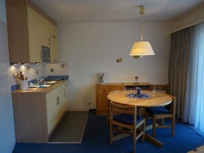 A compact kitchen with a dining area, a small table, and a ceiling fan. - Paradies 035 Appartement/Fewo, Bad, WC, 2-Bettwohnung 2-Bettwohnung by Interhome (Arosa)