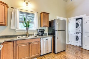 Una cocina con armarios de madera, lavavajillas, refrigerador y lavadora.