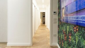 Een gang met een houten vloer, witte muren en een deur die naar een andere kamer leidt.