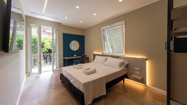 Een moderne slaapkamer met een groot bed, een bureau, een spiegel en een balkon met uitzicht.