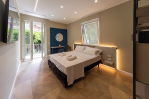 Ein modernes Schlafzimmer mit einem großen Bett, einem Schreibtisch, einem Spiegel und einem Balkon mit Blick.