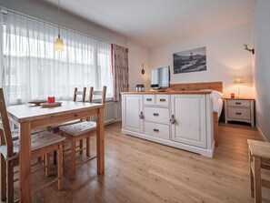 A modern kitchen with wooden cabinets, a dining table with chairs, a TV, and a painting on the wall. - Paradies 411 Appartement/Fewo, Bad, WC, 2-Bettwohnung 2-Bettwohnung by Interhome (Arosa)