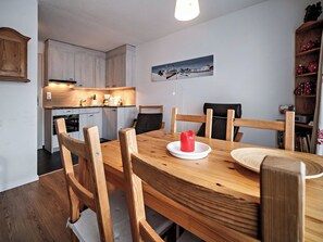 A dining area with a wooden table and chairs, a red candle, and a kitchen in the background. - Paradies 411 Appartement/Fewo,  , 2-Bettwohnung 2-Bettwohnung by Interhome (Arosa)