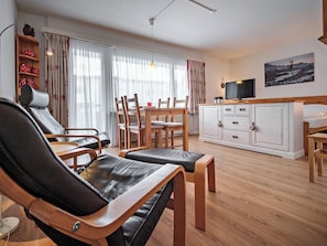 Una sala de estar con un sofá, una mesa de comedor con sillas, un televisor y un mueble.