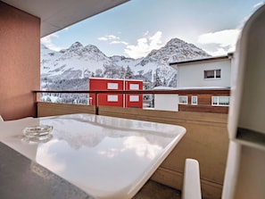 A balcony with a table and chairs, overlooking a snowy mountain landscape and buildings. - Paradies 411 Appartement/Fewo,  , 2-Bettwohnung 2-Bettwohnung by Interhome (Arosa)